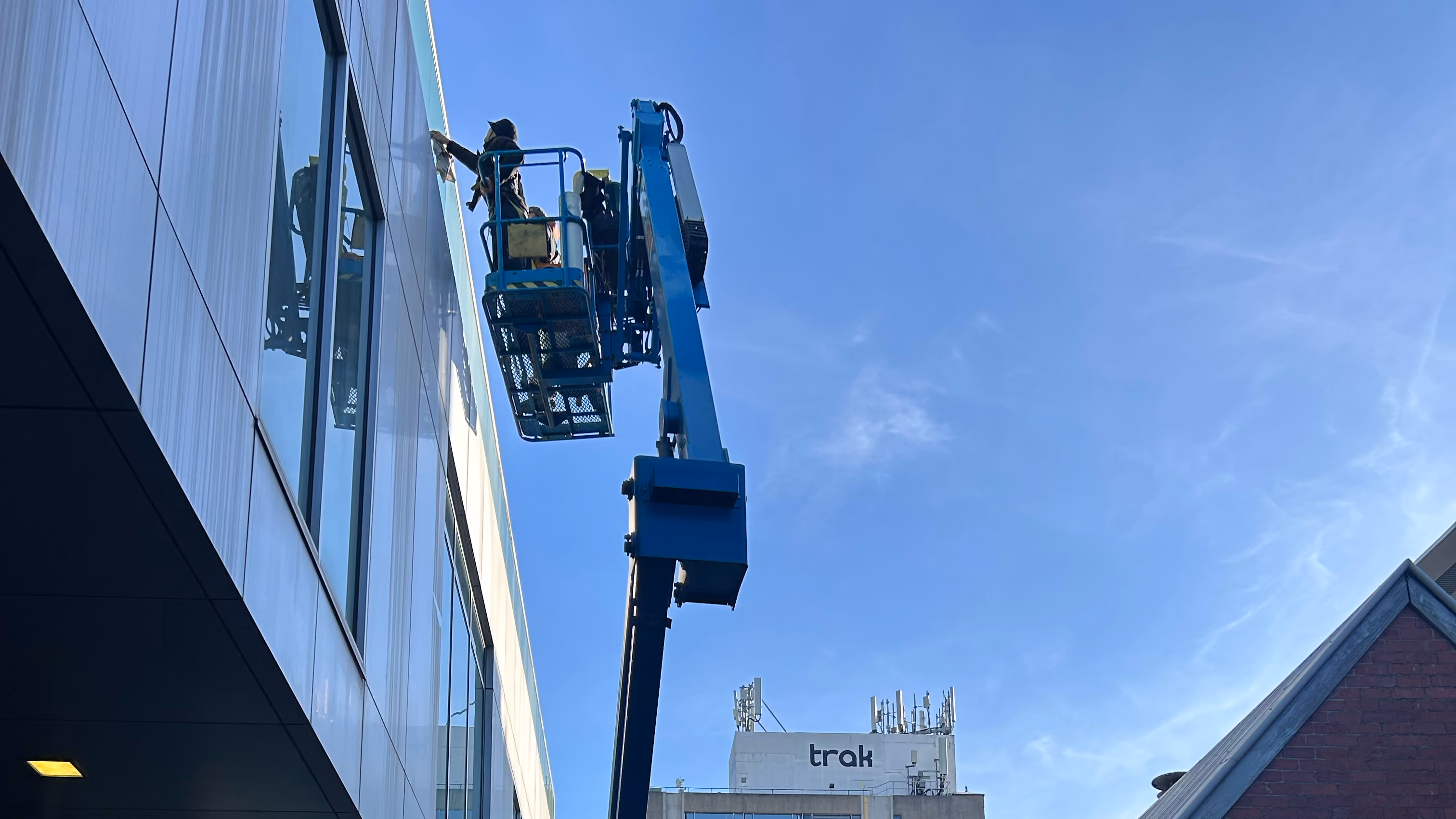 Bax Clean technician cleaning exterior windows using a boom lift