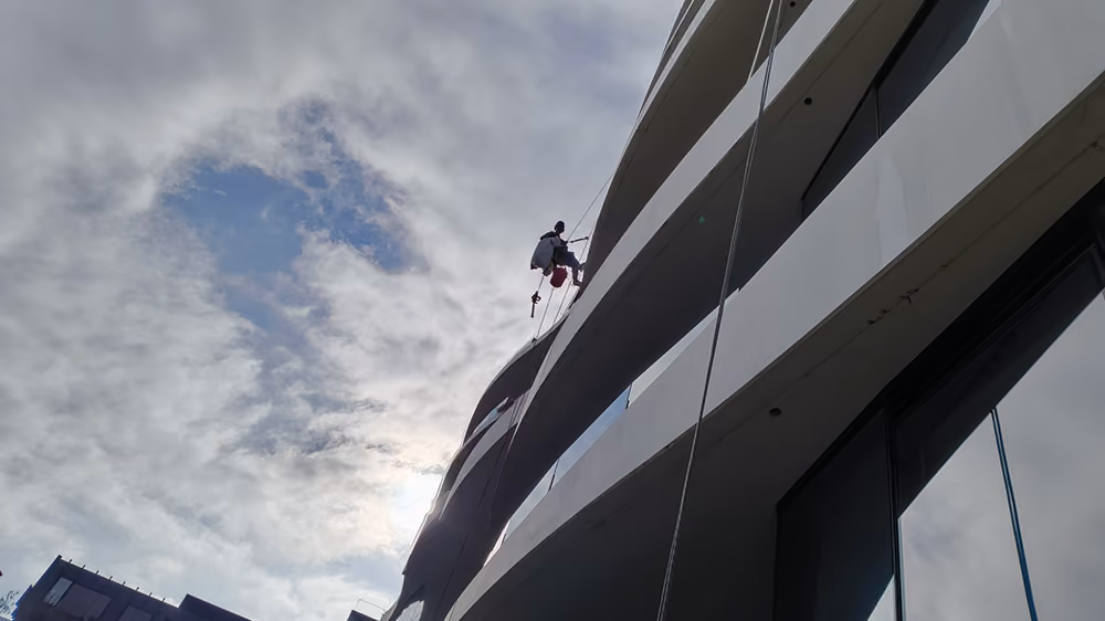 Bax Clean rope access technician working on a multi-storey residential building