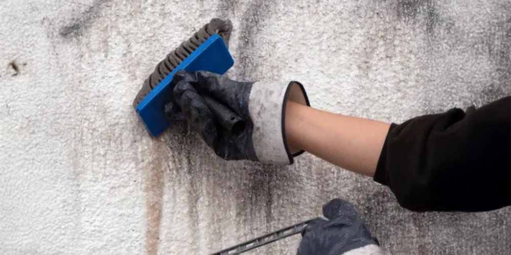 Scrubbing graffiti off a textured wall by hand in Doncaster.