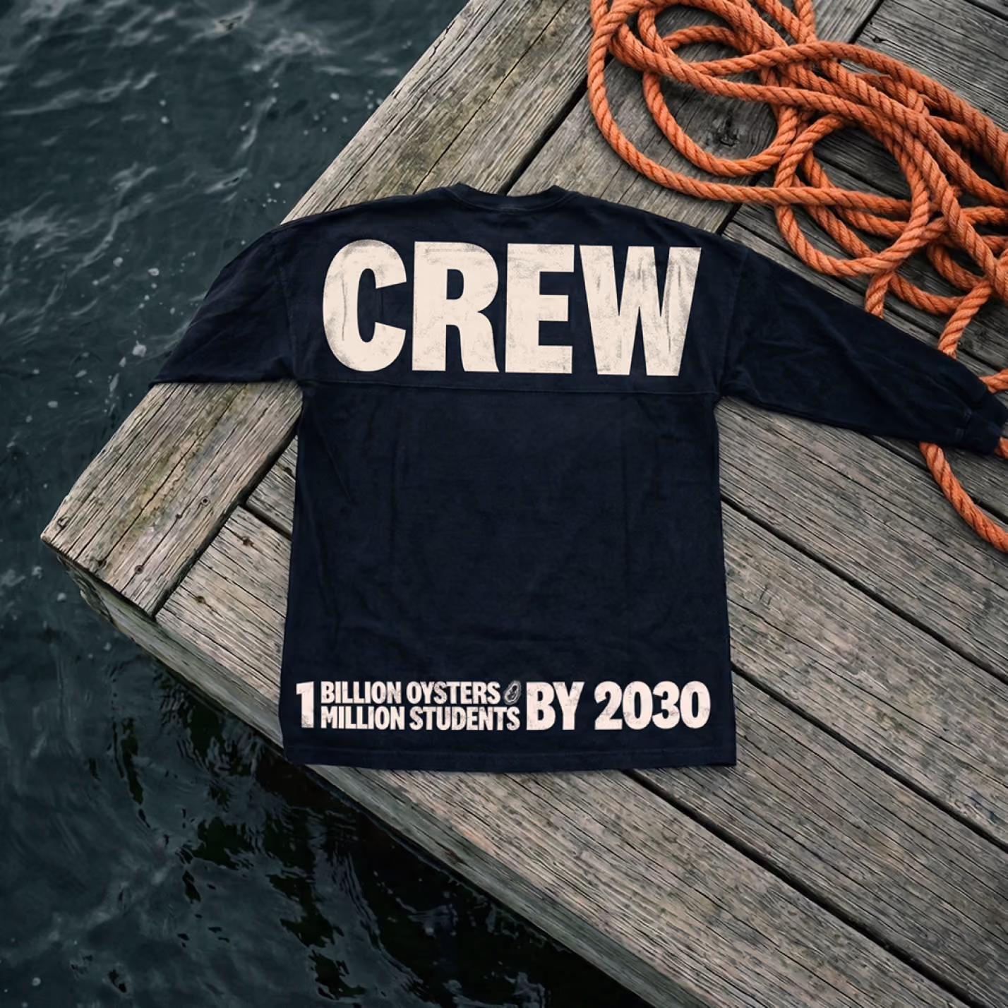 Navy long-sleeve crew shirt printed CREW and ‘1 billion oysters, 1 million students by 2030’, on a dock