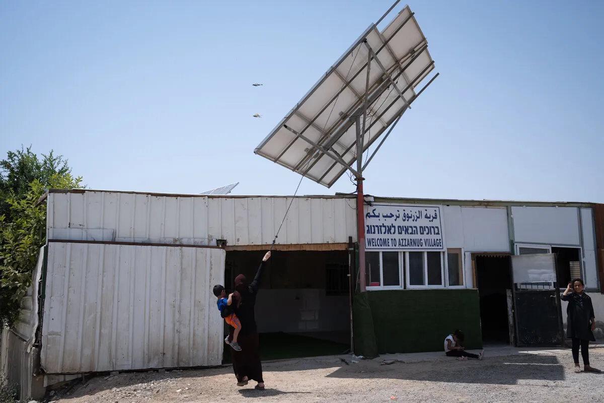 אישה בכפר הלא מוכר אלזרנוג מסובבת פאנל סולארי כדי שיעקוב אחר השמש (צילום ארכיון ביאה בר קלוש)
