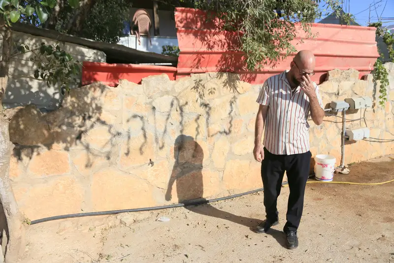 תושב הכפר ביתא בגדה ליד גרפיטי "נקמה" שרוסס בו. צילום: רויטרס