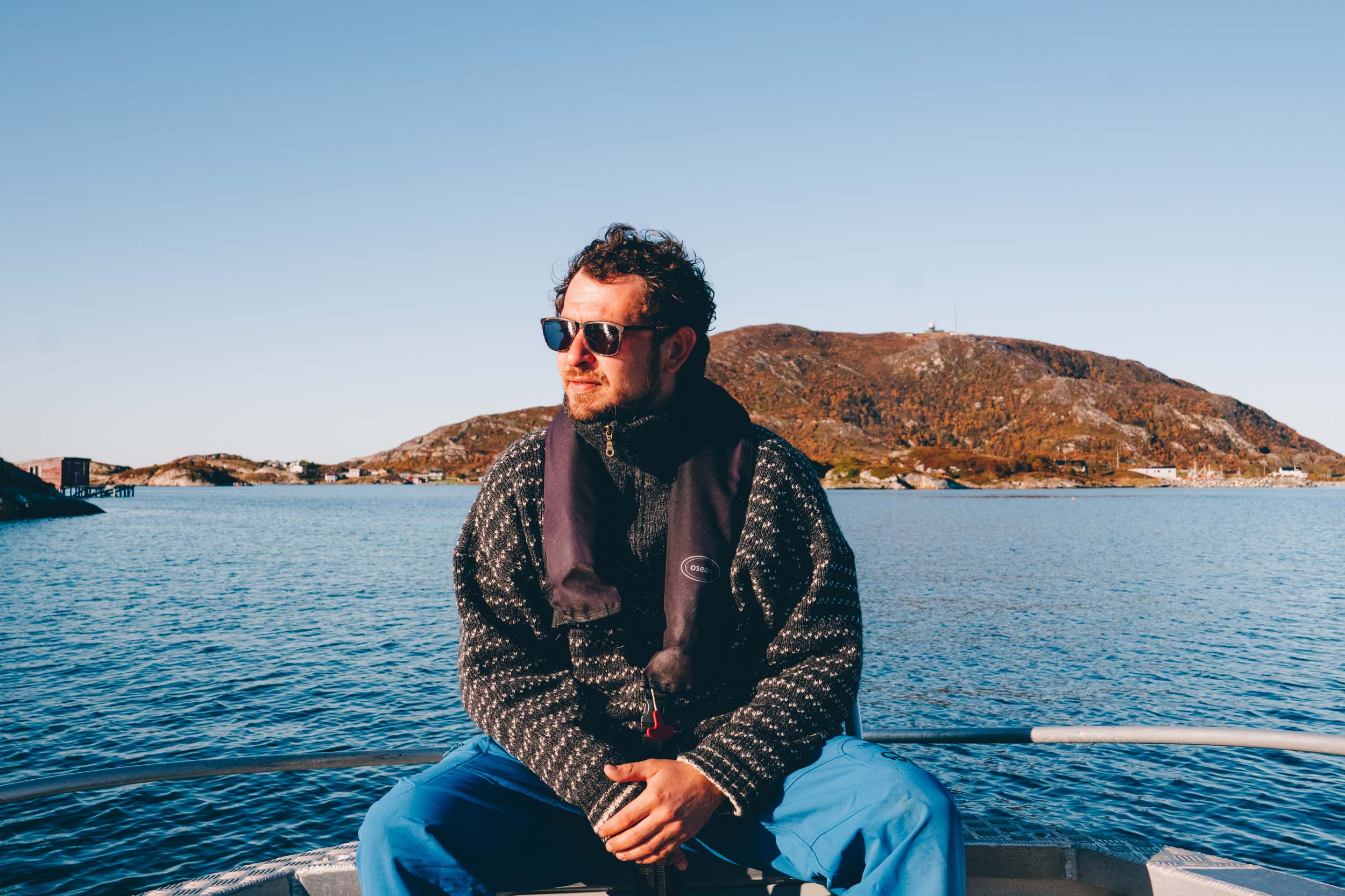 Mann med solbriller sitter i en båt på havet