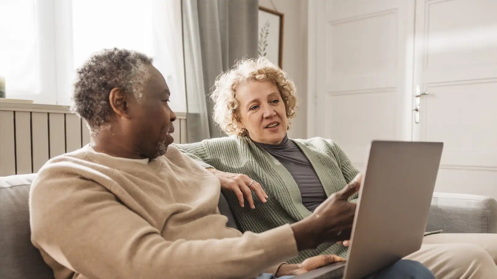 Woman and man sitting on couch, looking at laptop