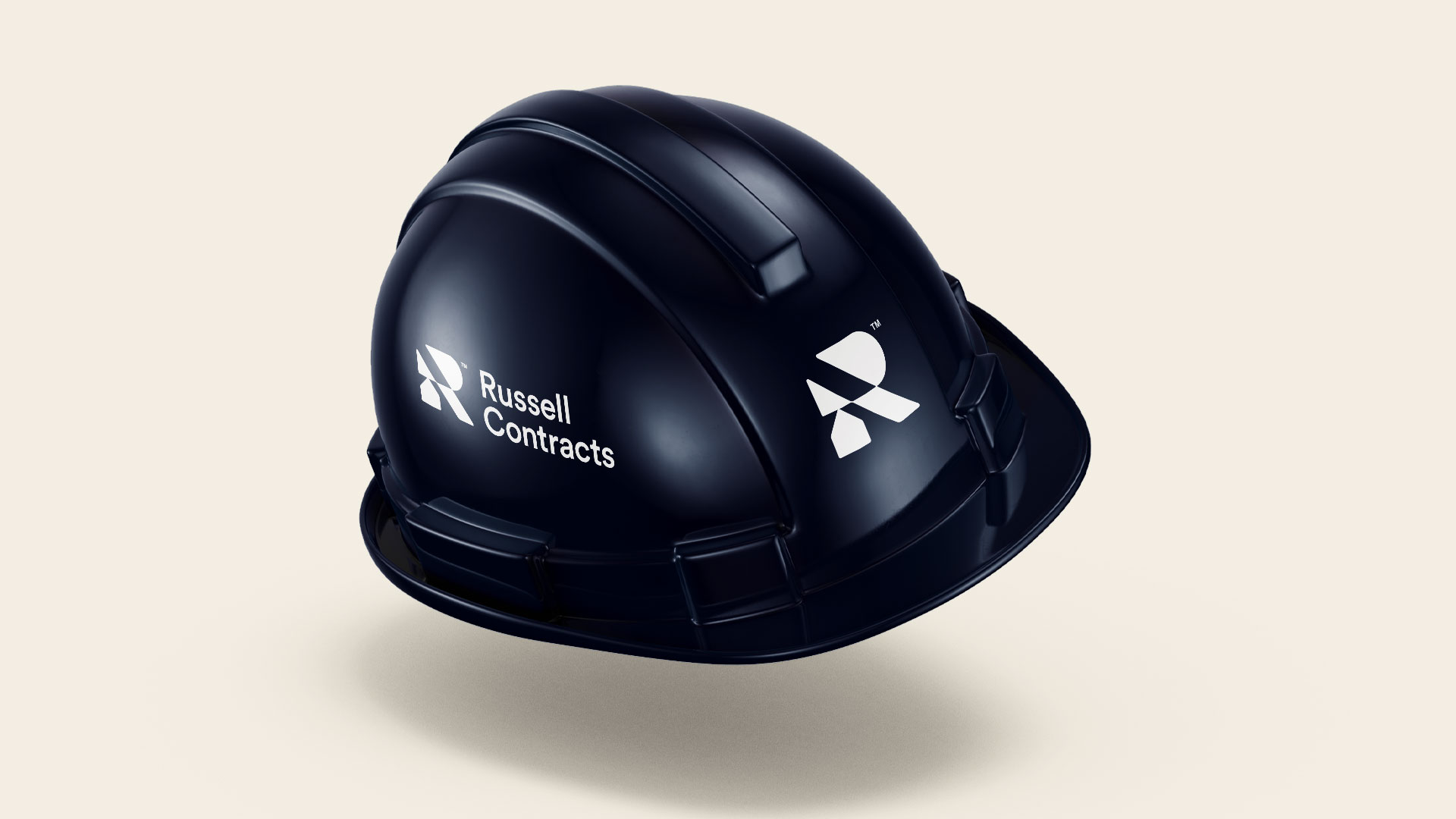 Russell Contracts logo and standalone R symbol applied to a navy construction hard hat.