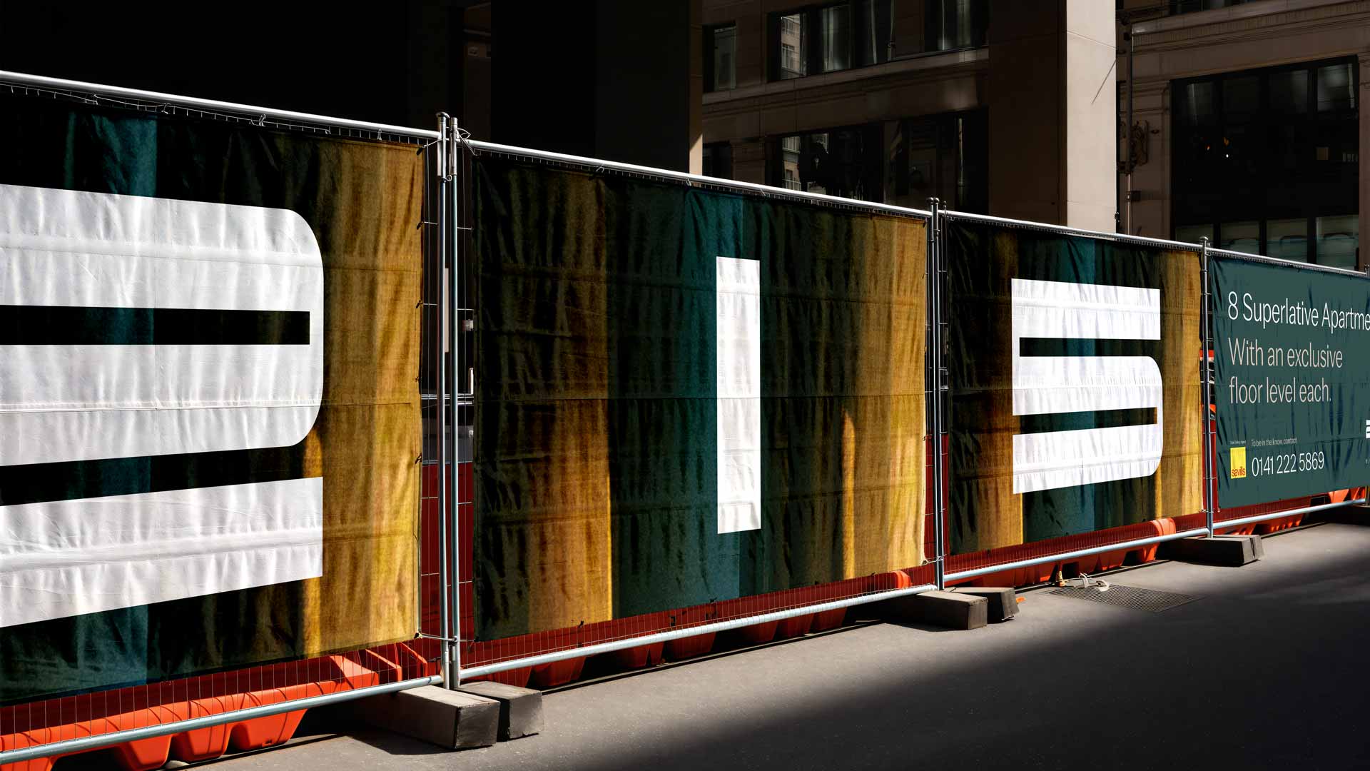 White 215 numerals across three site-fence panels, with green-and-gold fabric imagery and an apartment sales panel.
