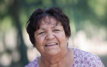 Portrait of Doreen from shoulders up wearing a purple shirt and smiling at the camera