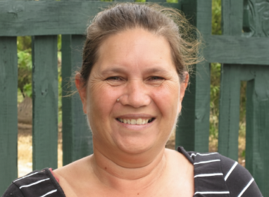 Portrait of Kay from shoulders up wearing a Black and white stripe shirt and smiling at the camera