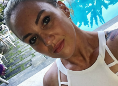 Picture of Dee outside wearing white looking at the camera with a pool in the background
