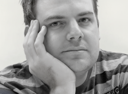 Black and white picture of John with his head resting in his hand, looking at the camera