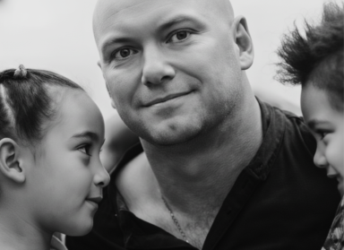 Portrait of Kim smiling at the camera holding his two kids