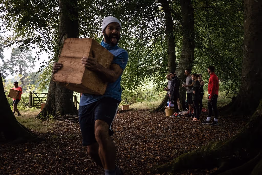 a man carrying a large box, exercising in the woods