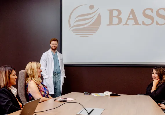 doctor presenting a BASS Medical Group presenting to a group at meeting table