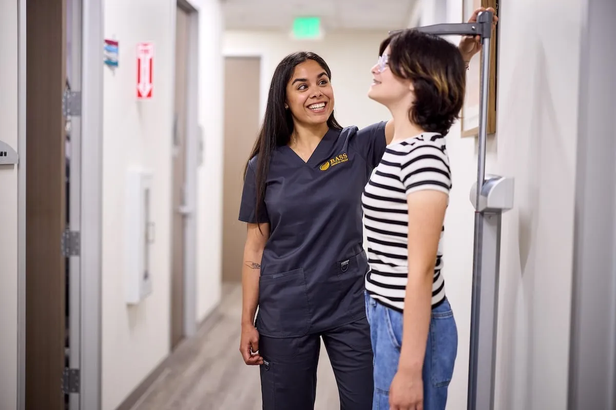 A BASS employee measuring a patient's height