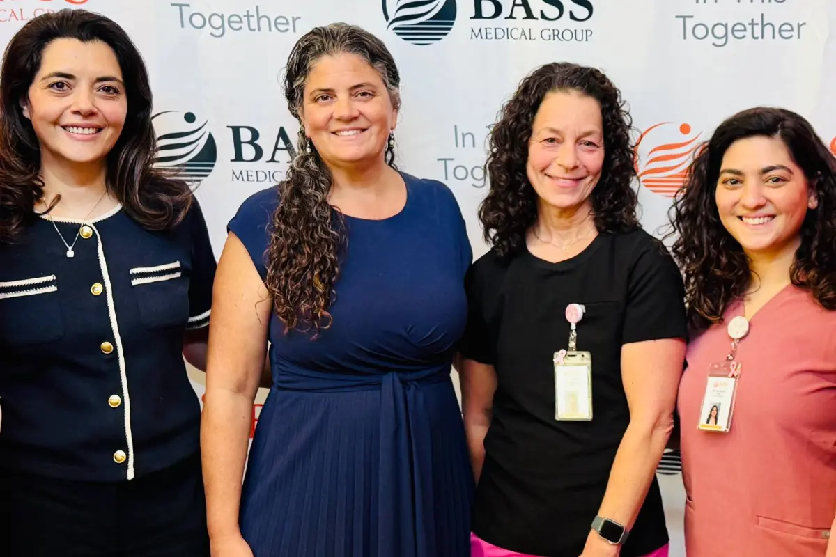 From left to right: Dr. Soheila Azghadi, Dr. Danielle Bertoni, Rachelle ‘Shell’ Portner, and Nicole Daisa, NP, standing in front of a BASS Medical Group backdrop at the Gregory Rhodes MD Cancer Center.