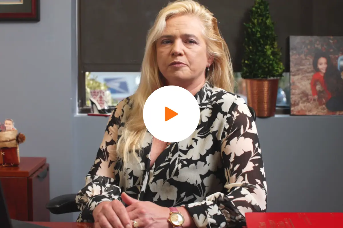 Dr. Michaela Straznicka, thoracic surgeon at BASS Medical Group, sitting at her desk with a computer and medical books in the background, featured with a play button overlay for the lung cancer risk factors video.