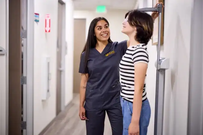 Healthcare professional measuring a young patient’s height in a clinic.