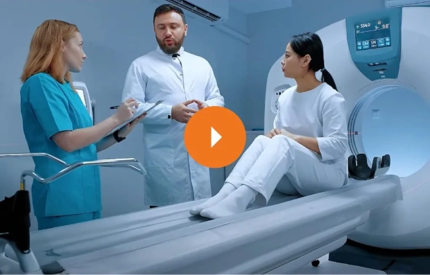 A doctor and MRI technician explain to the patient how the imaging machine works.