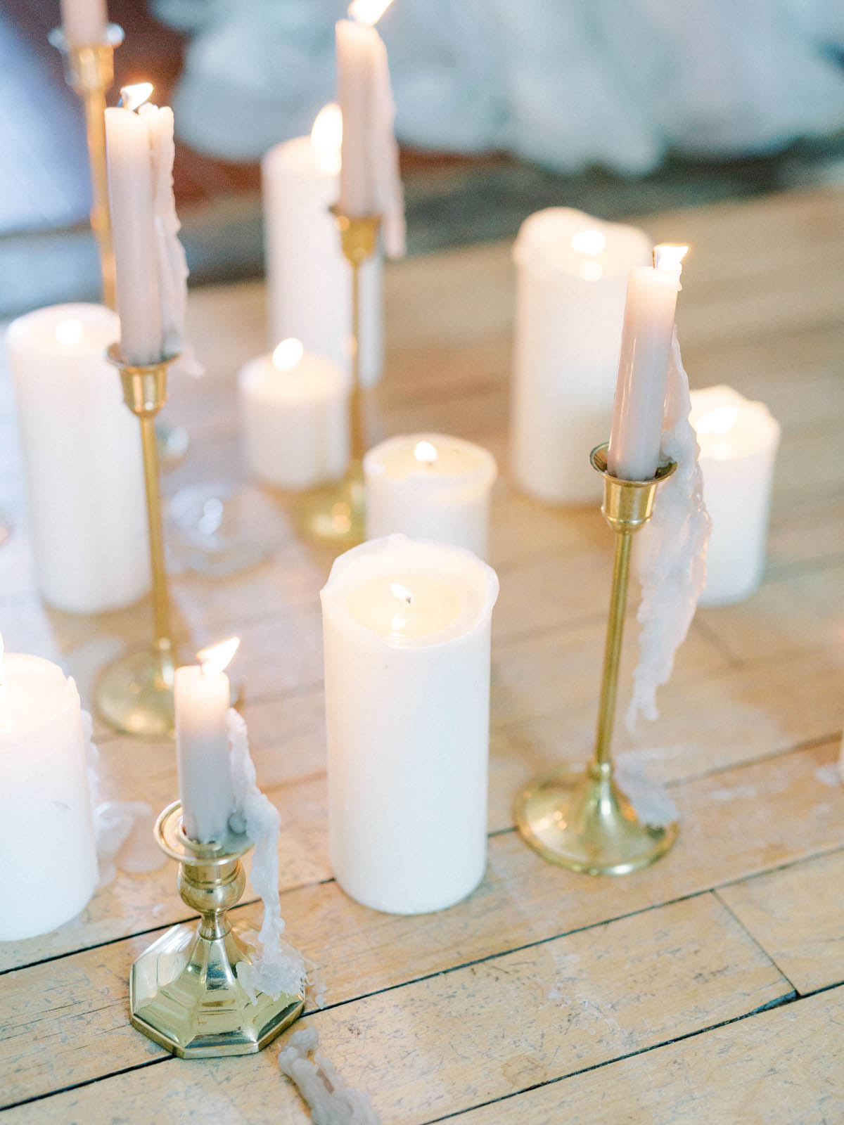 Brass candlesticks and pillar candles arranged on the wood floor