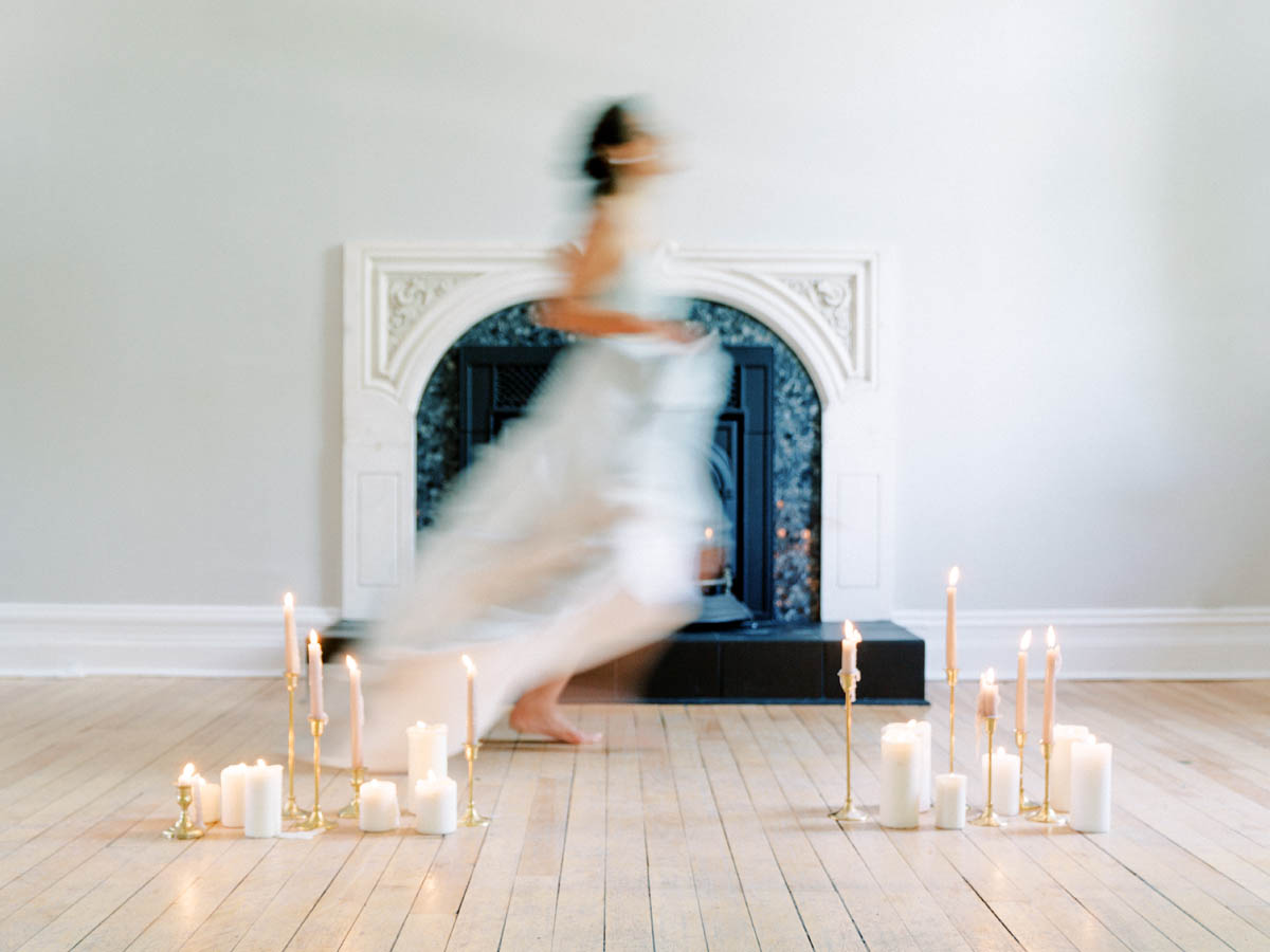 Bride dancing barefoot in front of the fireplace surrounded by candles