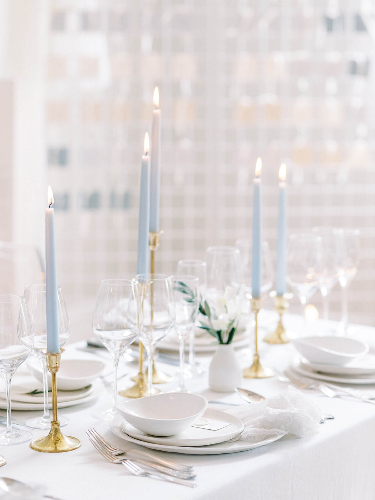 Tablescape detail with blue tapers, glassware and a white bud vase