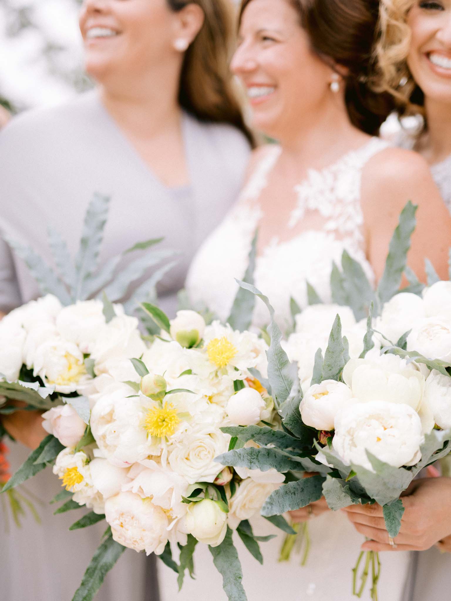 Close up of the white peony and rose bouquets held by the bride and her bridesmaids