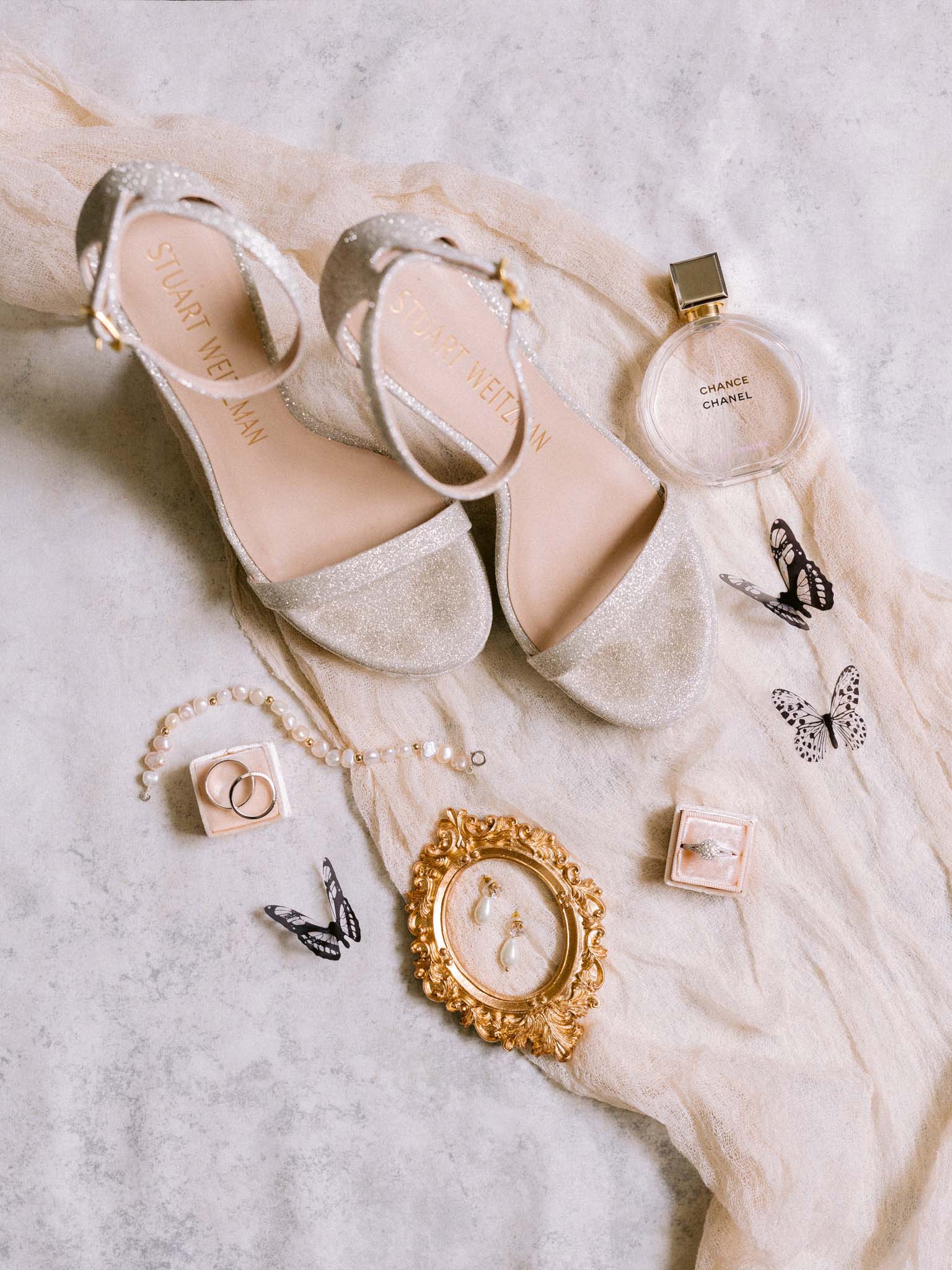 Bridal details on ivory gauze: glitter Stuart Weitzman sandals, Chanel perfume, pearl jewellery and the wedding rings