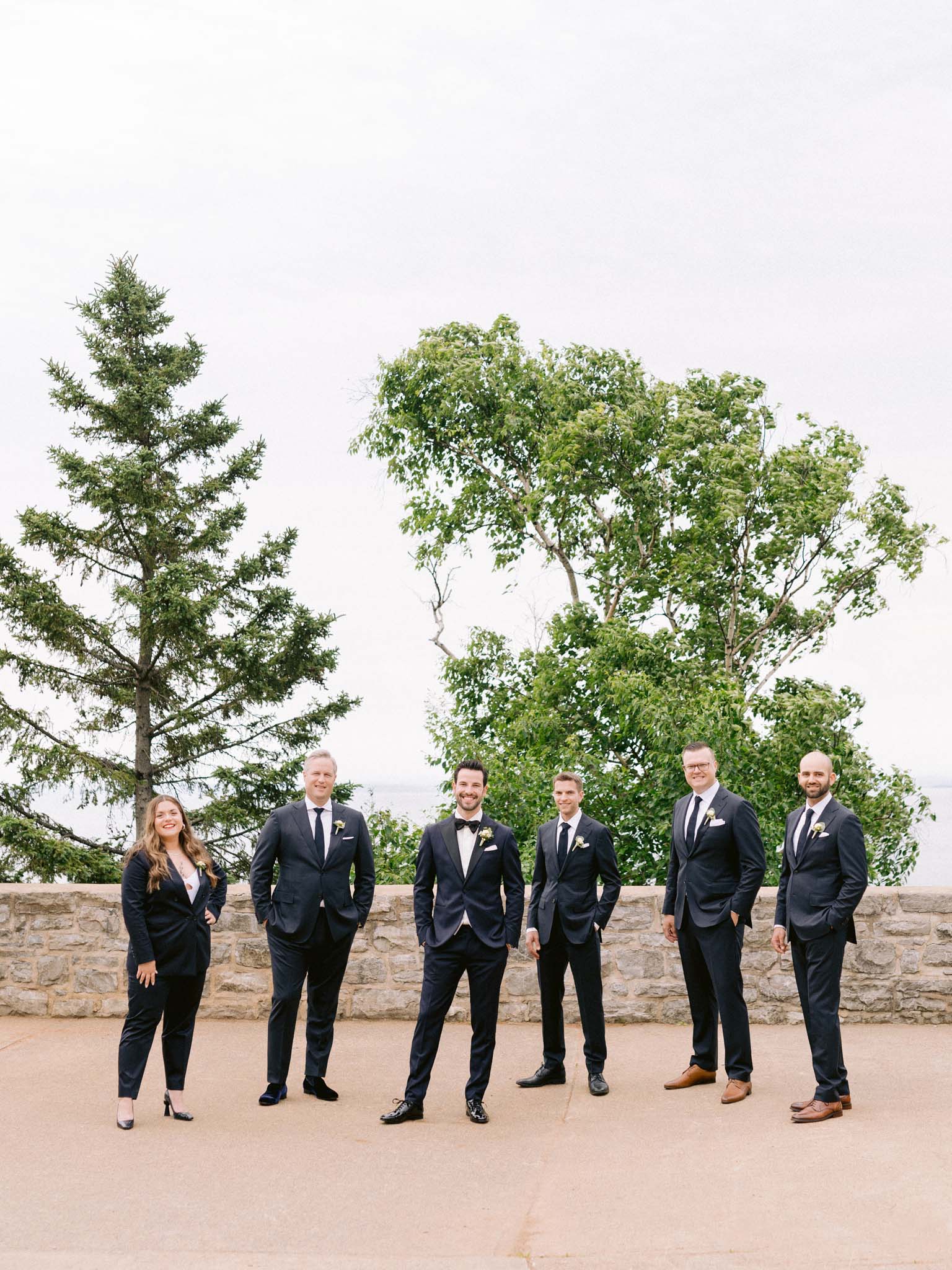 Groom and his wedding party in navy tuxedos on the terrace, the St. Lawrence behind them