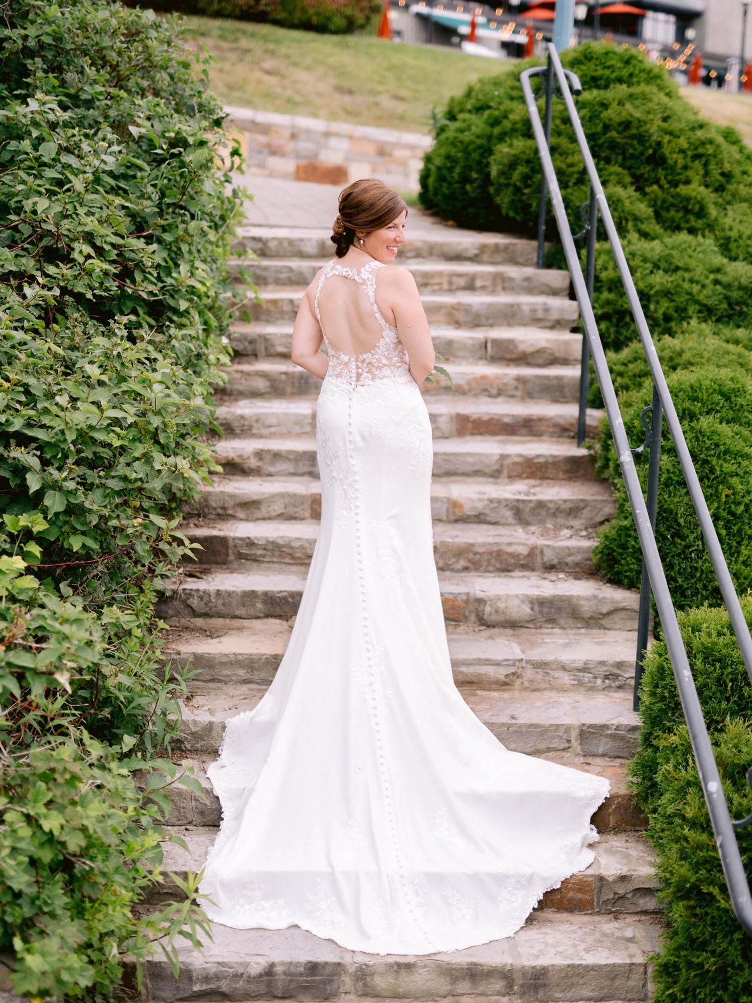 Bride looking back over her shoulder on the garden steps, her train spread behind her