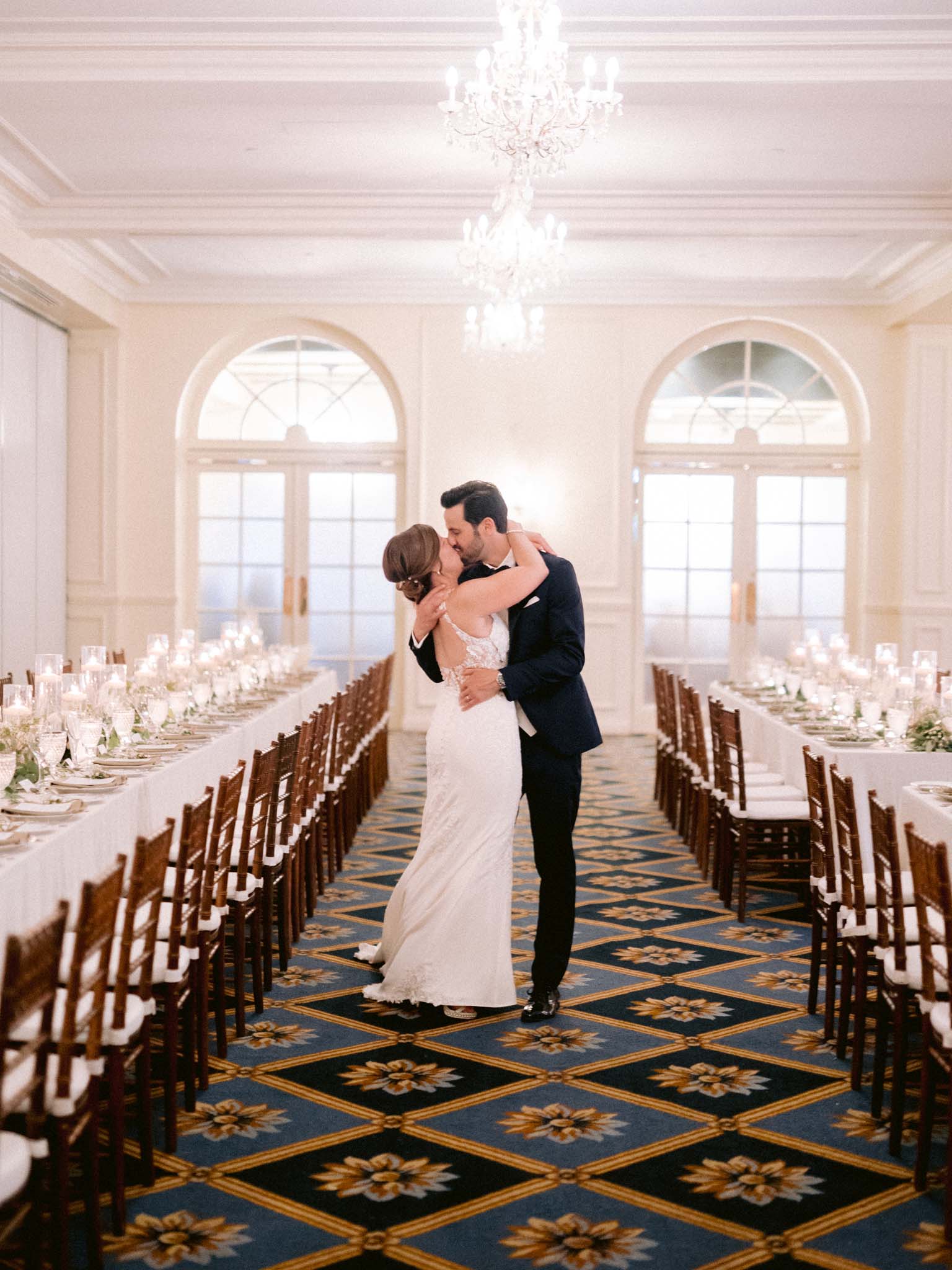 Bride and groom kissing alone in the empty reception room before the guests arrive
