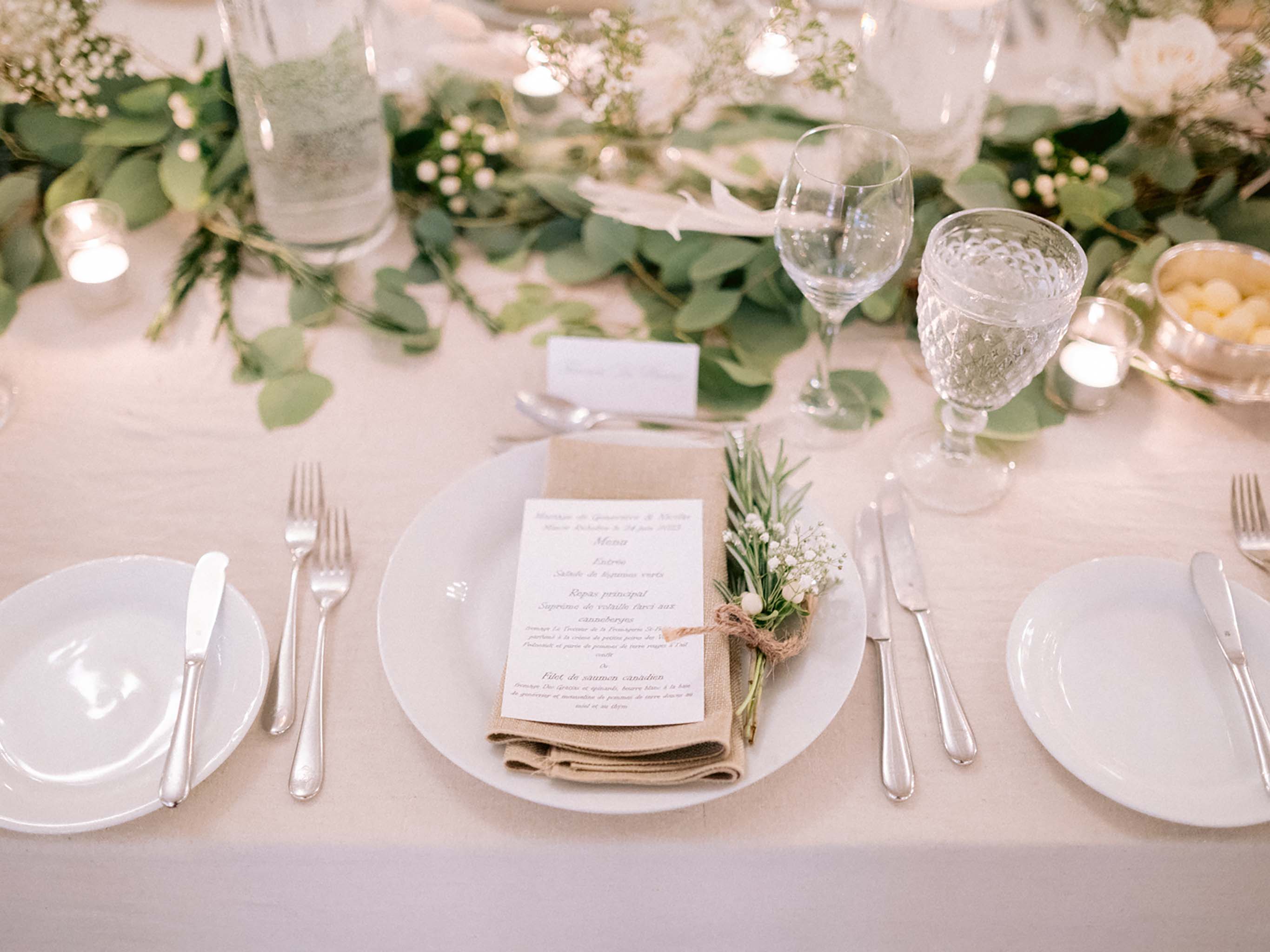 Place setting with a burlap napkin, a rosemary sprig and a menu card printed in French