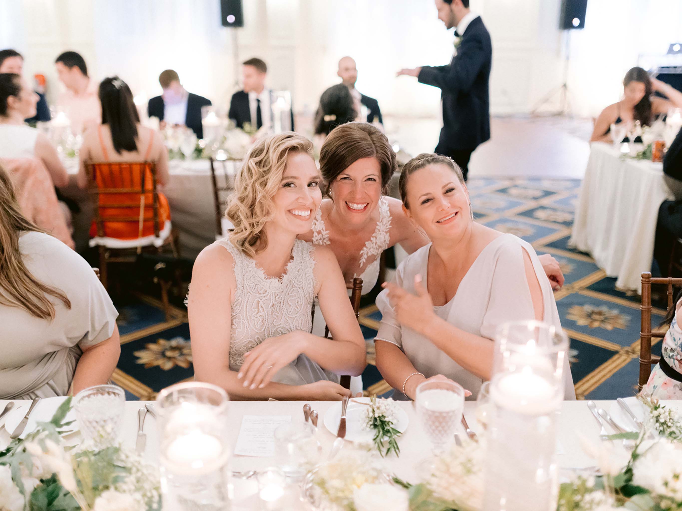 Bride laughing with two of her bridesmaids at the head table