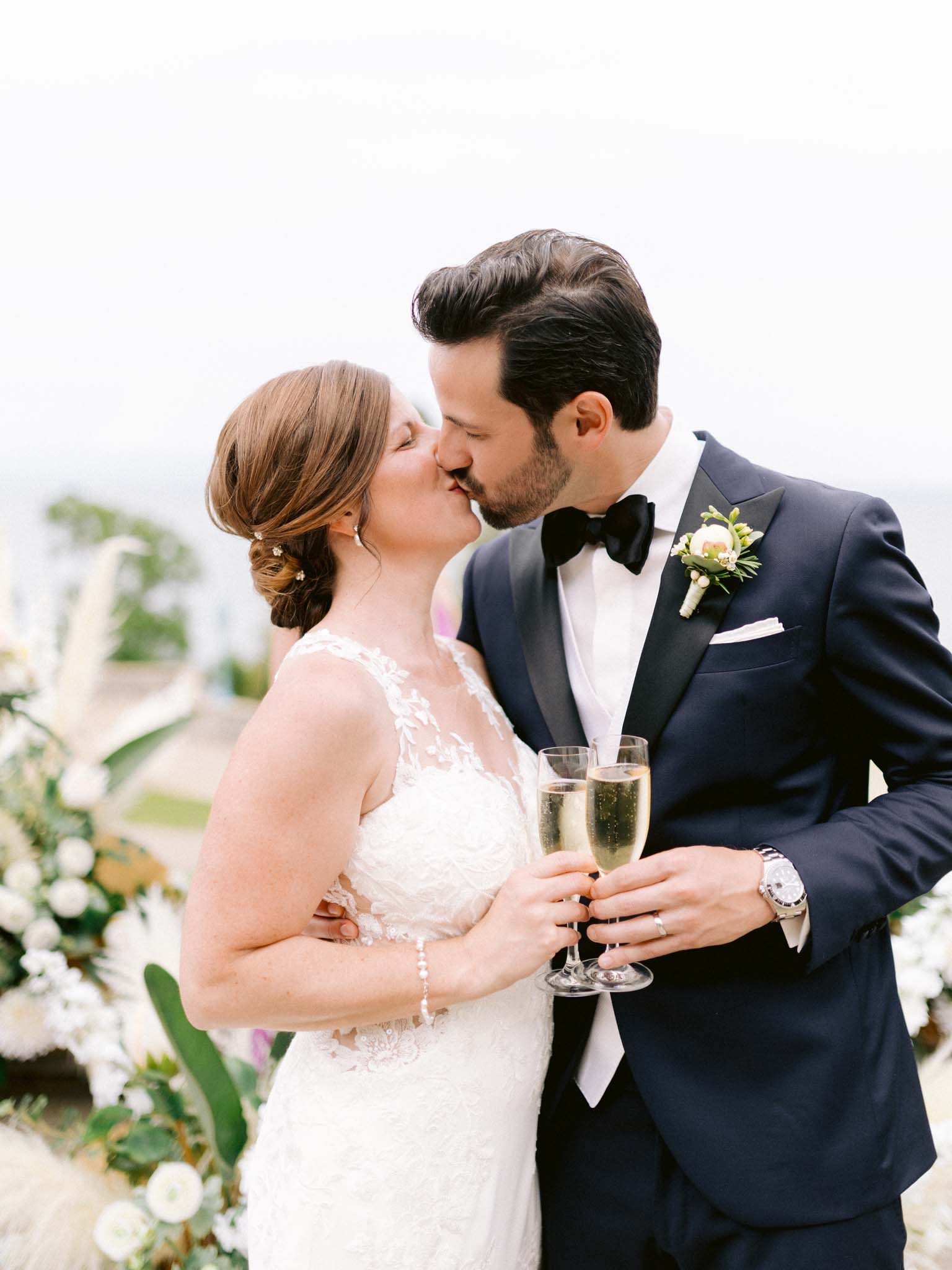 Bride and groom kissing over their champagne glasses just after the ceremony