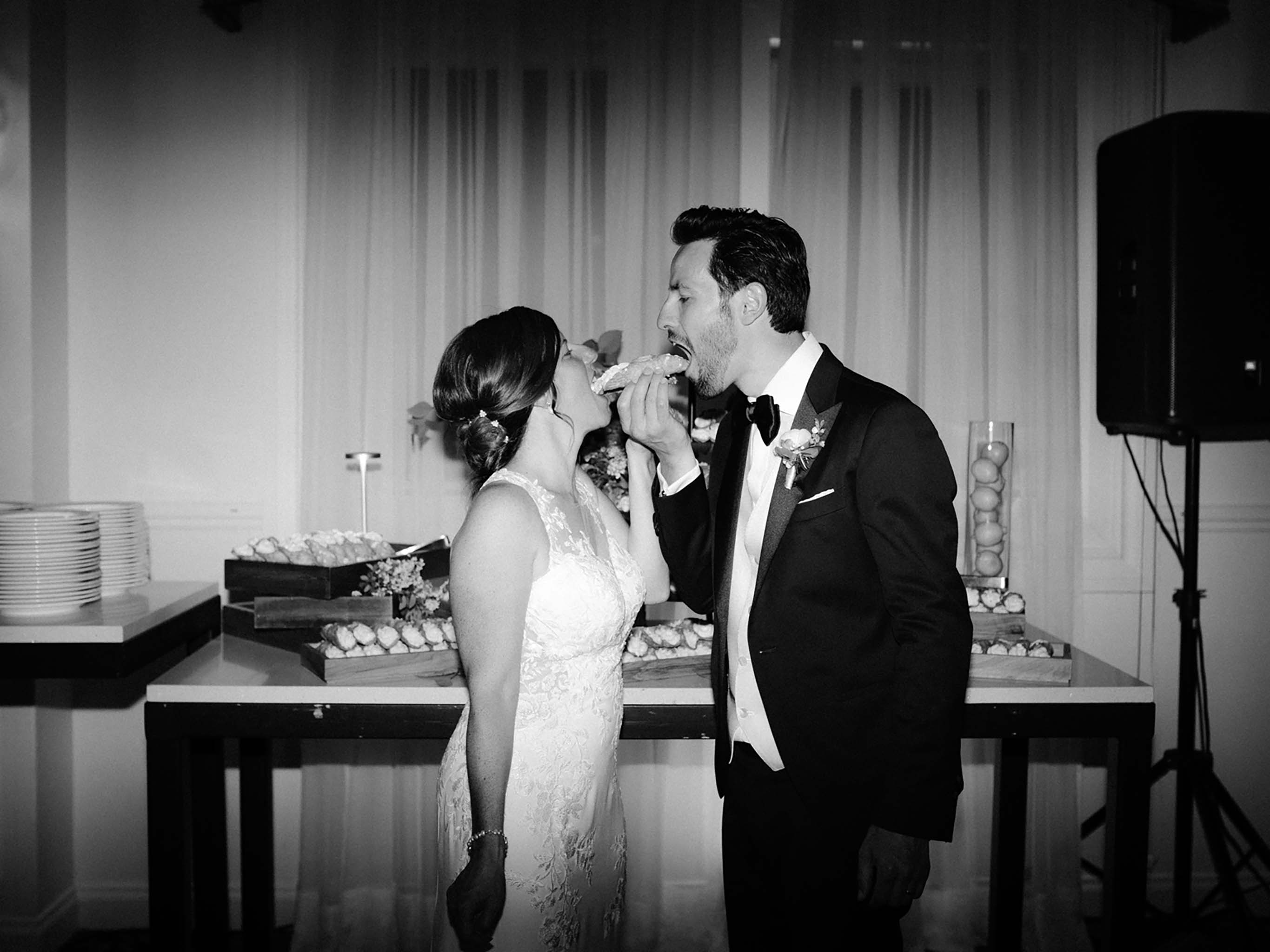 Bride and groom feeding each other cannoli in place of a wedding cake