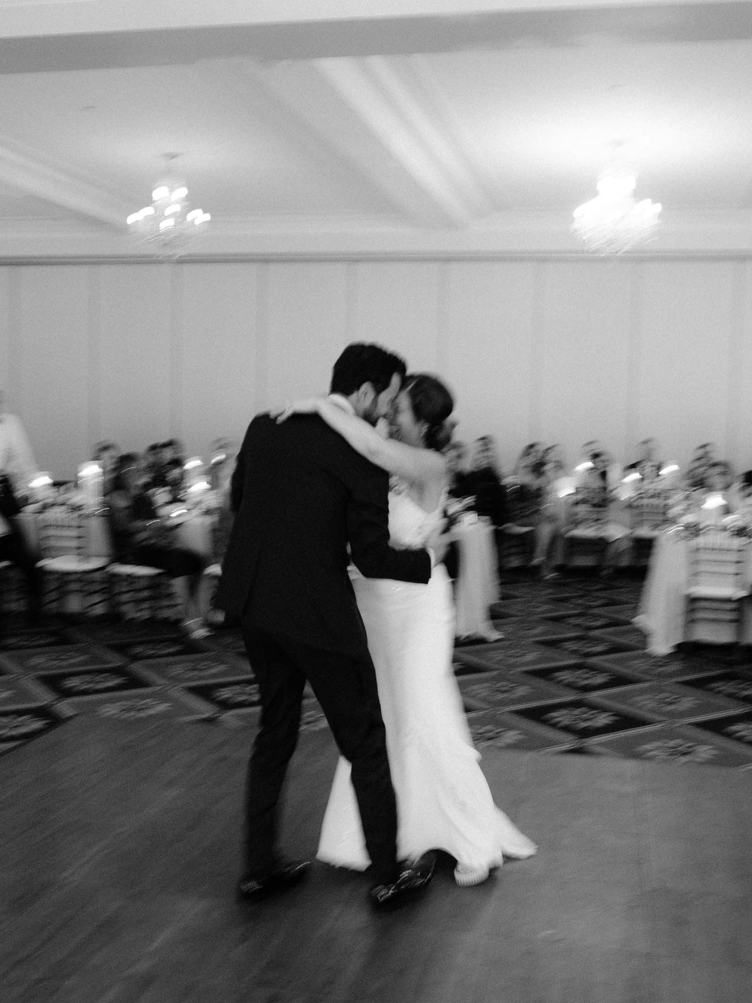 Bride and groom kissing during their first dance, caught in motion blur