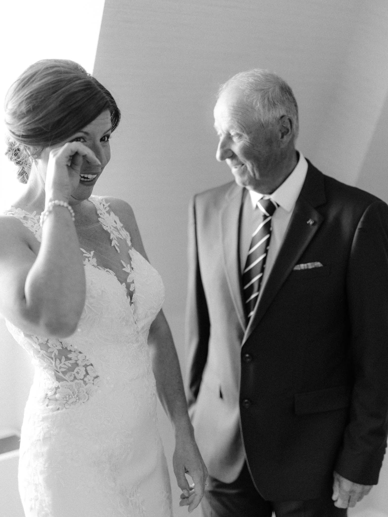 Bride wiping away tears beside her father after their first look