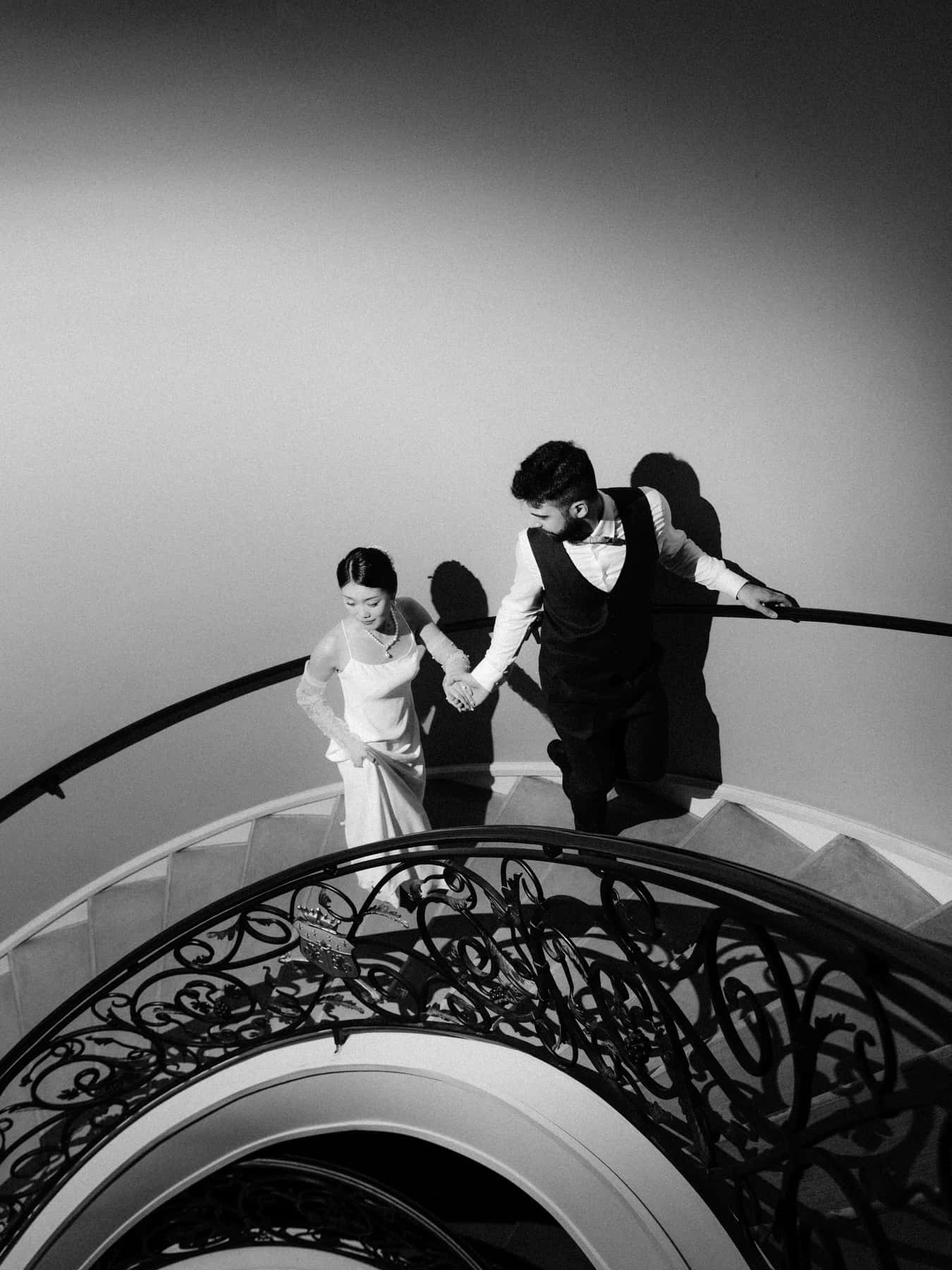 Couple montant l'escalier en colimaçon, vu d'en haut à travers la balustrade en fer forgé