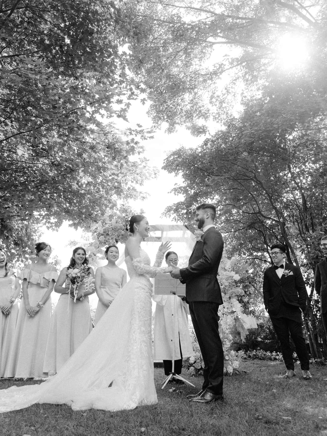 Mariés échangeant leurs vœux sous les arbres, les demoiselles d'honneur à leurs côtés