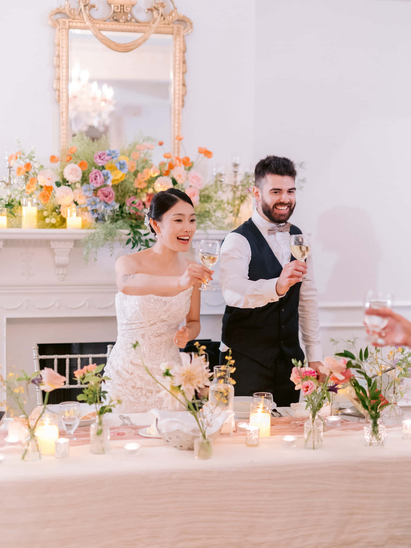 Mariés levant leur verre à la table d'honneur devant le foyer
