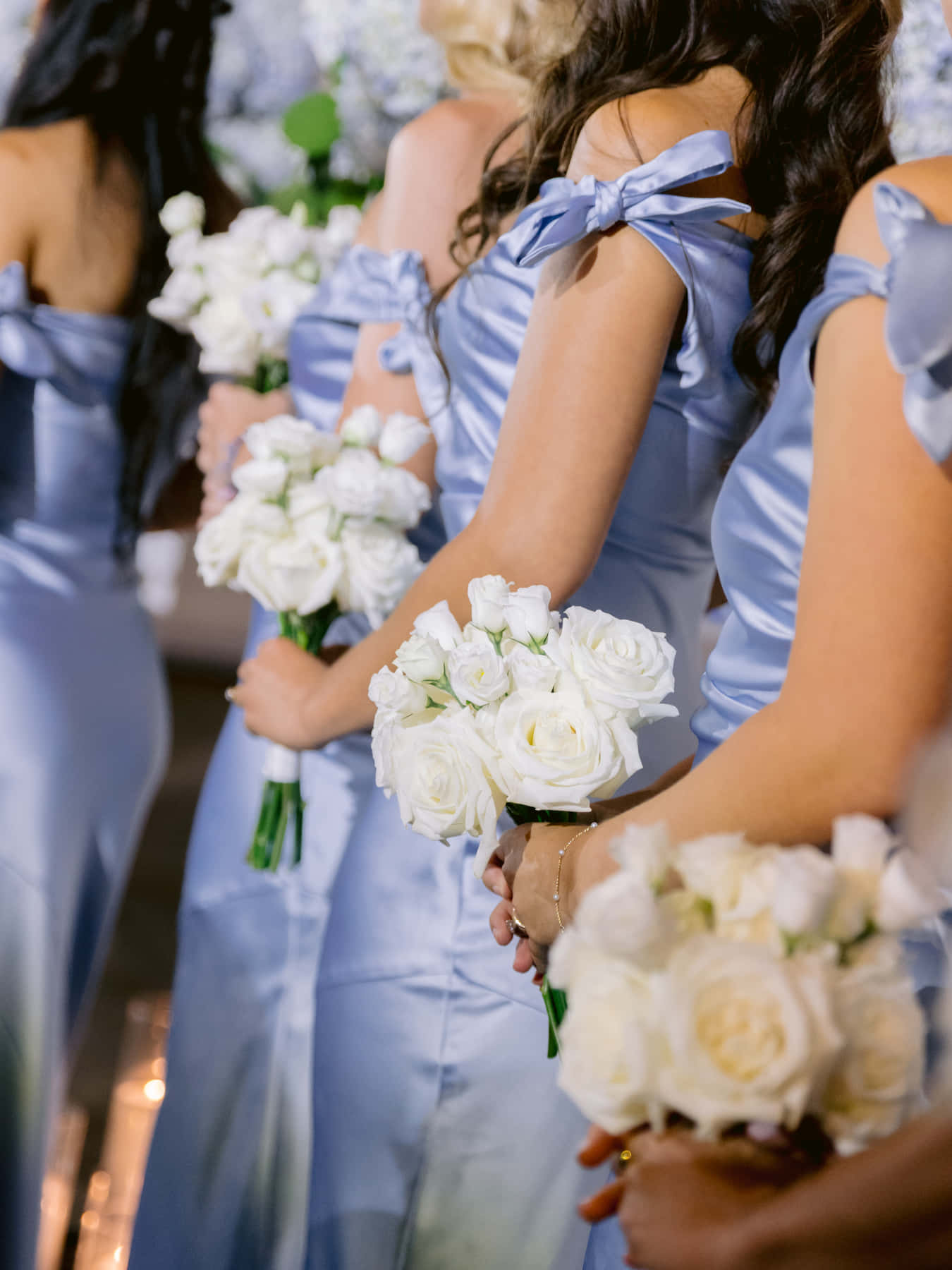 Bridesmaids holding white rose bouquets during the ceremony