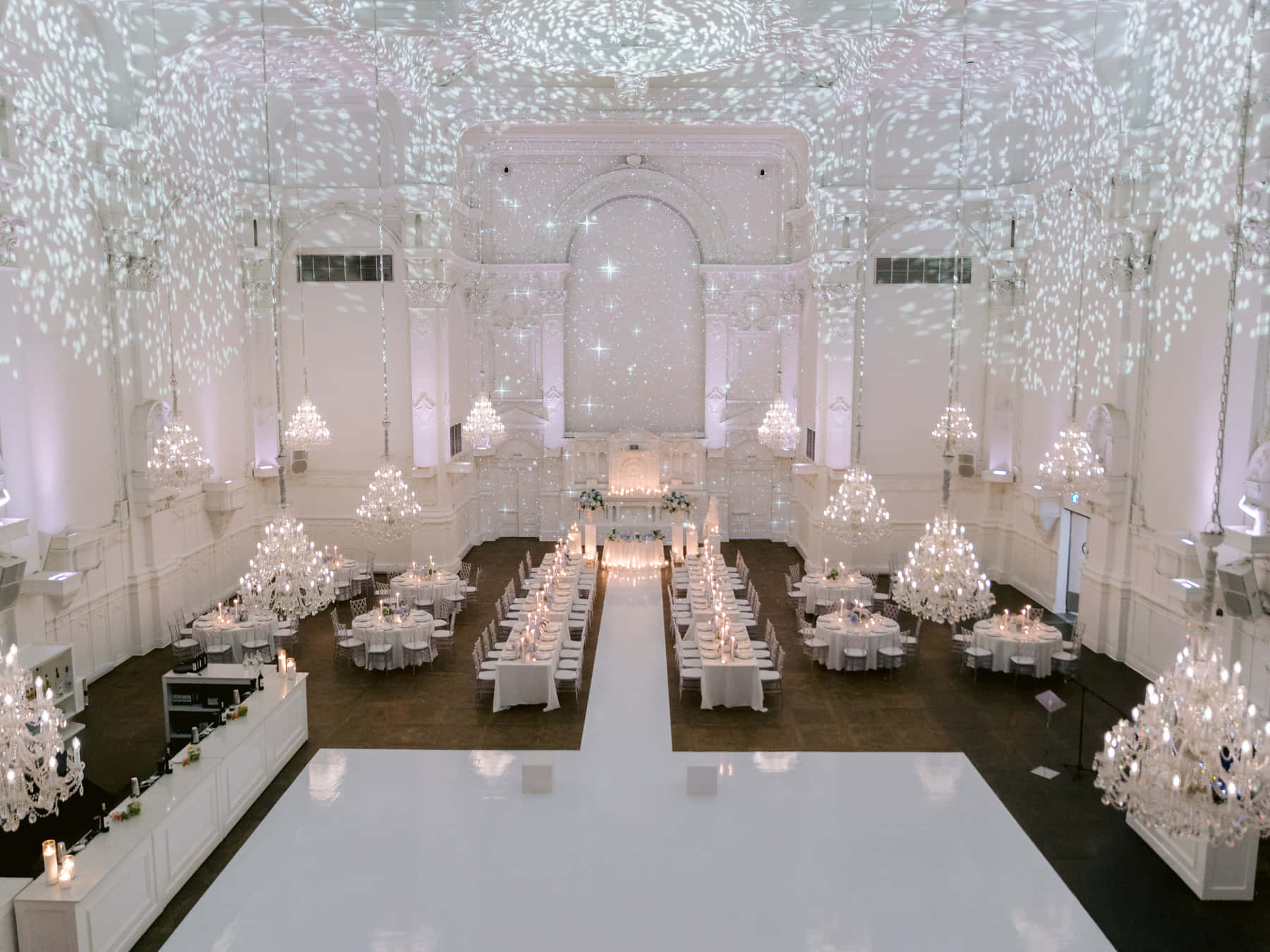 Grand Salon at Maison Principale set for dinner, seen from the mezzanine, with chandeliers and a white dance floor