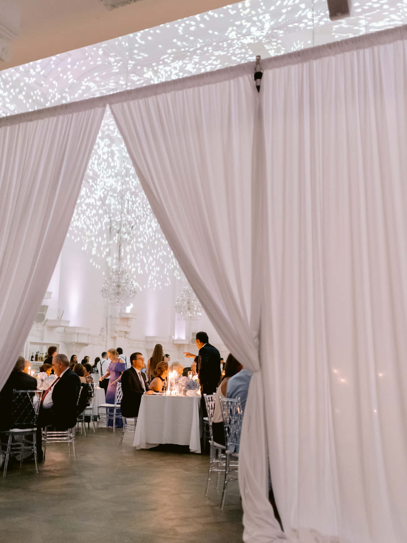 White drapes opening onto the reception in the Grand Salon