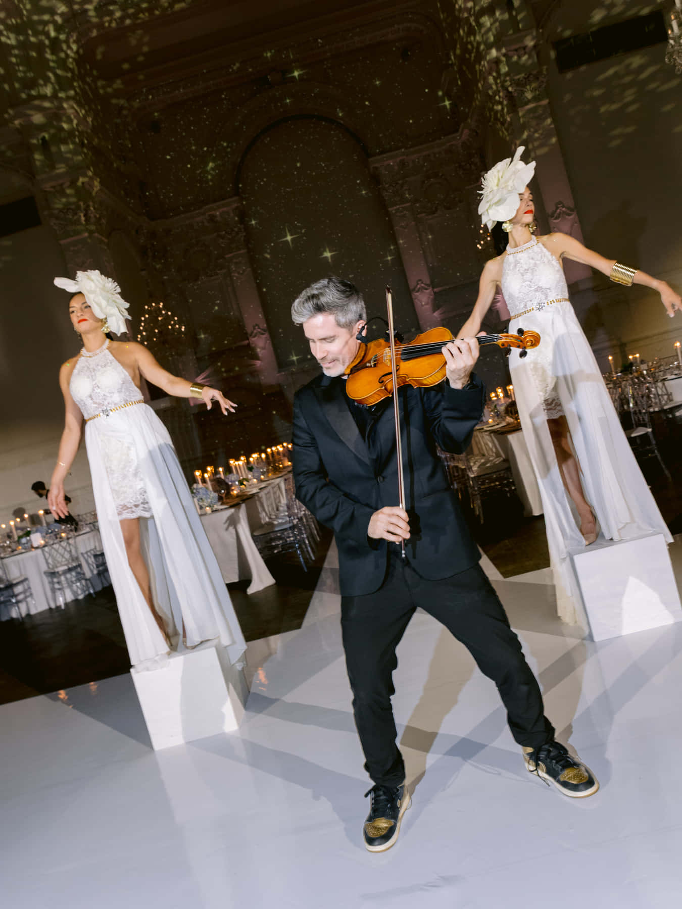 Violinist and two dancers on pedestals performing on the dance floor