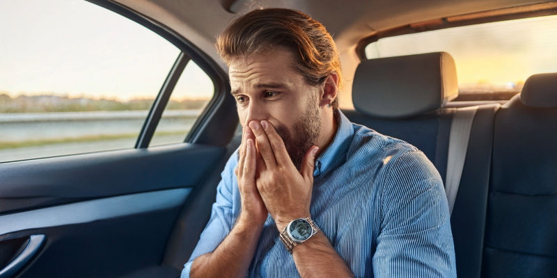 Nauseous man in passenger seat experiencing motion sickness.