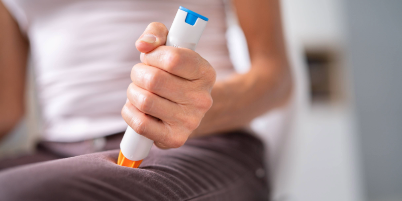 Woman sticking an EpiPen in her thigh to stop her severe allergic reaction known as Anaphylaxis.