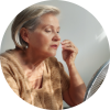 Sweating elderly person sitting in front of a fan, trying to cool off from extreme heat.