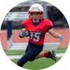 Young kid running with a football in protective gear on a multi-purpose field.