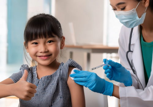 Young girl receiving a vaccination while giving a thumbs-up, symbolizing confidence and support for immunization.