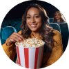 Adult woman eating popcorn from a classic striped popcorn bucket while seated in a dark movie theater.