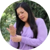 Woman in purple top holding her wrist in pain.